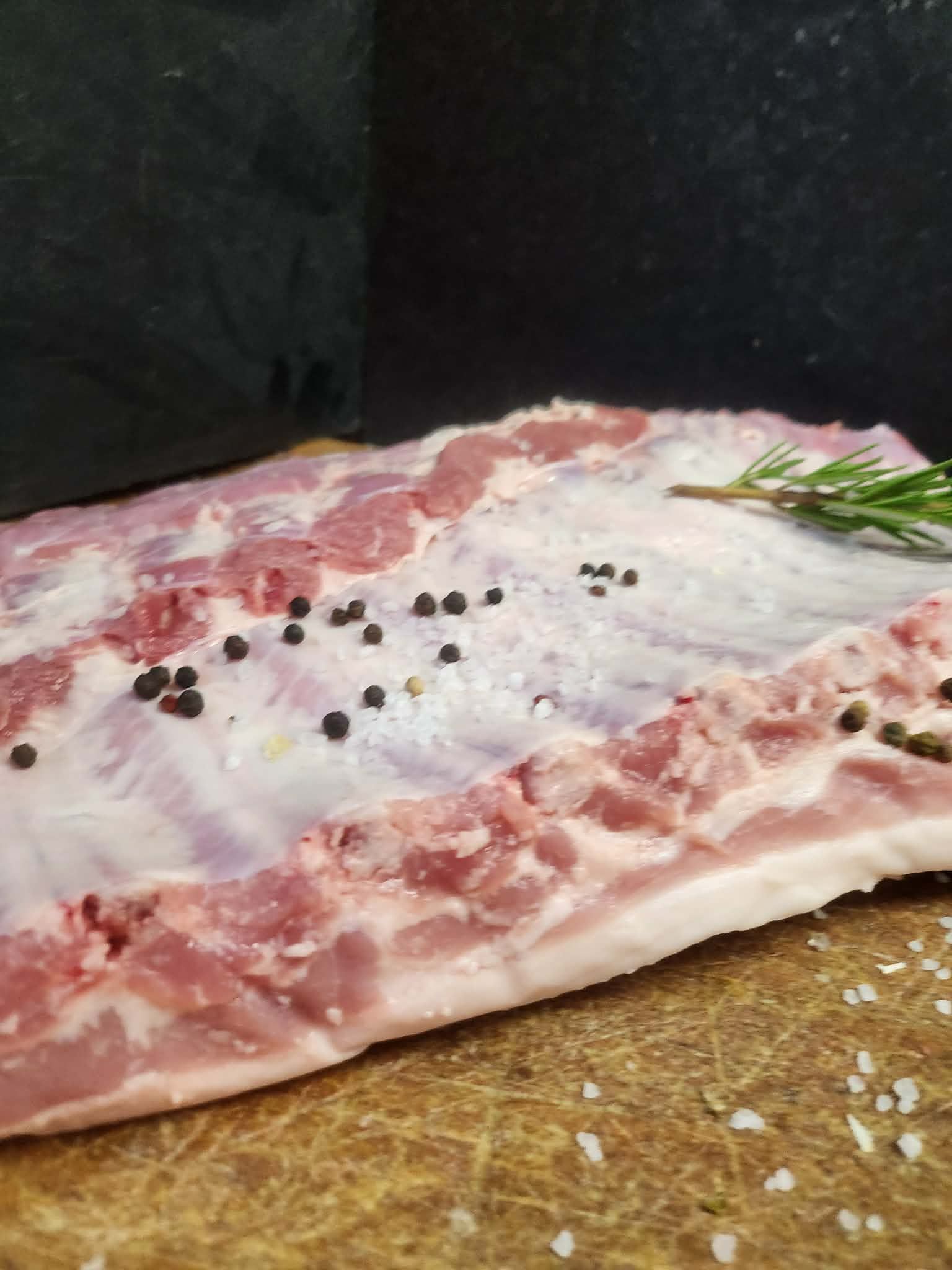 Fresh rack of pork ribs seasoned with sea salt and peppercorns