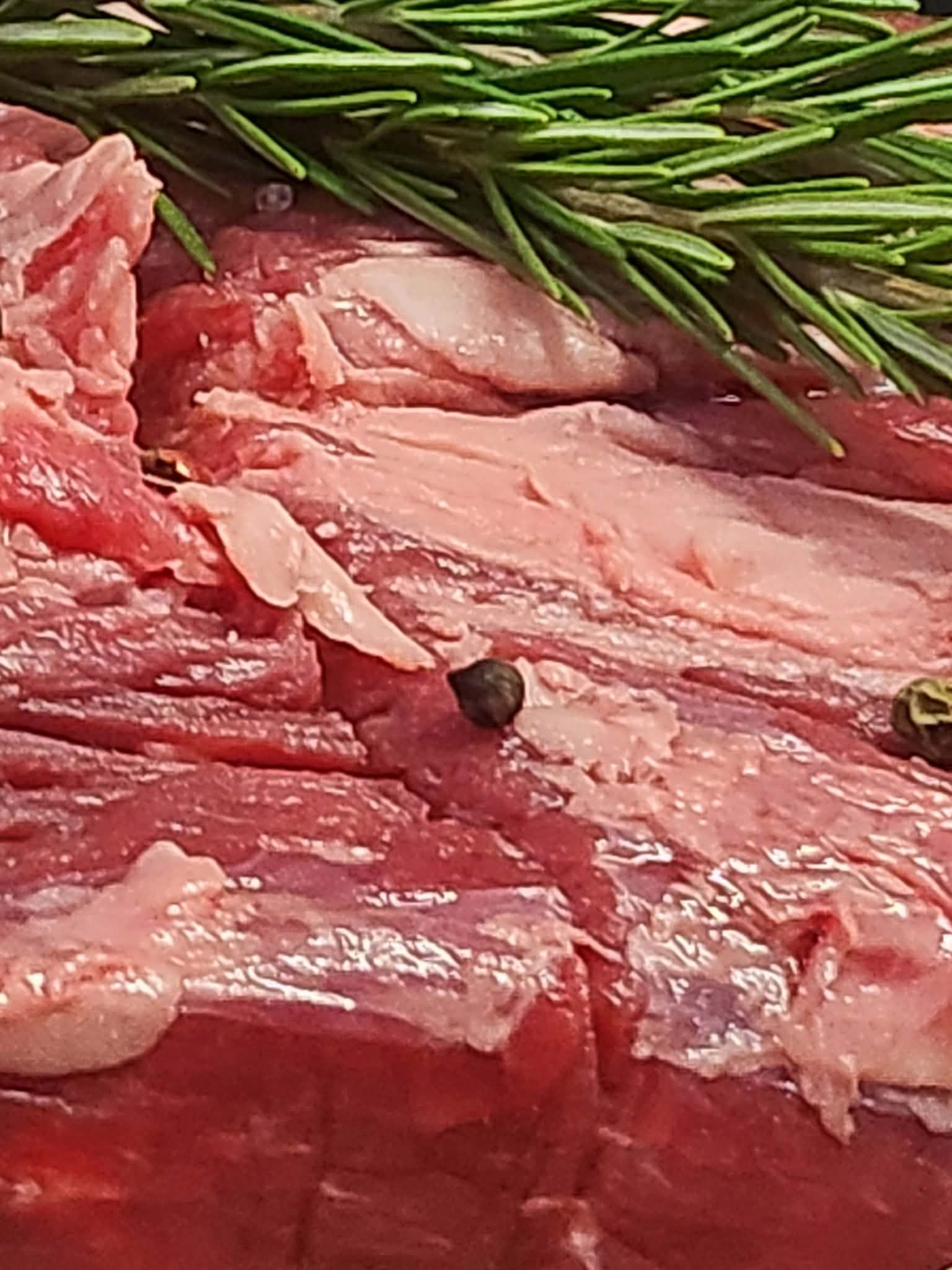 Freshly cut steak with green peppercorns and rosemary on the counter